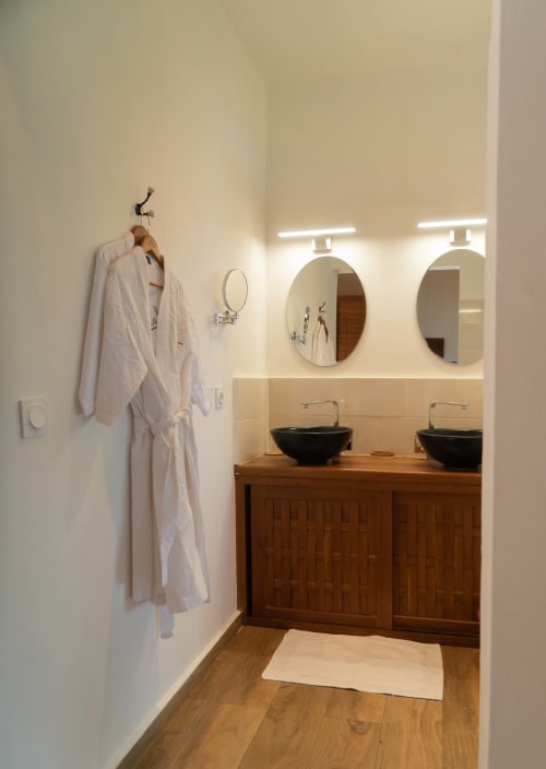 Salle de bains moderne de la Belamandy Lodge à Nosy Be avec vasques noires rondes et miroirs circulaires