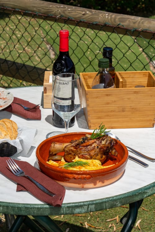 Geroosterde eend met polenta geserveerd op terracotta bord bij Hotel Balcón De Los Montés in Colmenar, met wijn en uitzicht buiten