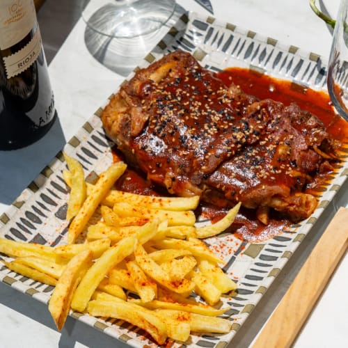Costillas glaseadas con semillas de sésamo y papas crujientes doradas del restaurante Hotel Balcón De Los Montés en Colmenar