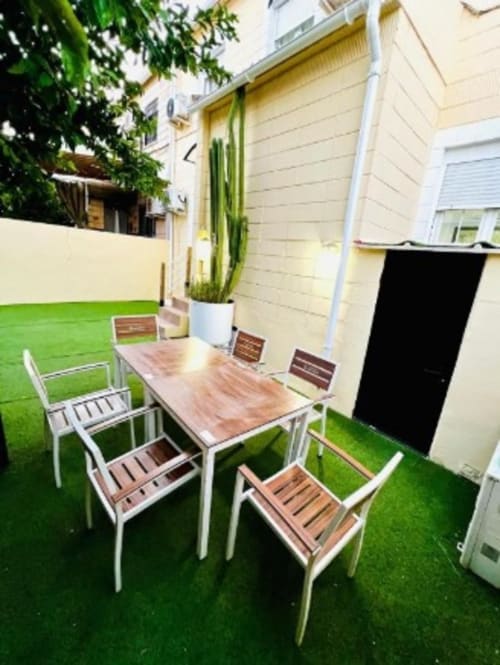 Moderno patio con mesa de comedor, sillas, césped artificial y cactus en maceta del apartamento Gestyp-AT en Mérida
