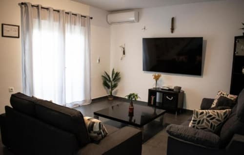 Moderno salón en apartamento Domus Citrus del hotel Gestyp-AT, Mérida con muebles negros, TV de pantalla plana y vistas a la ciudad