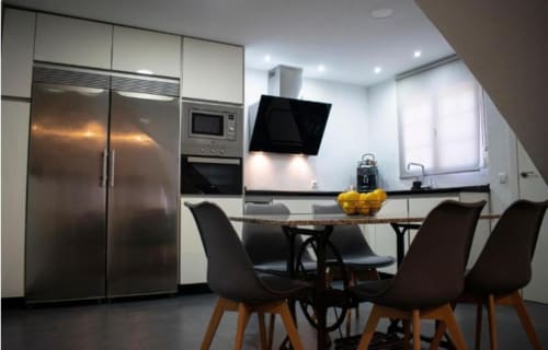 Cocina y comedor modernos del apartamento Domus Citrus en el hotel Gestyp-AT de Mérida con electrodomésticos de acero inoxidable