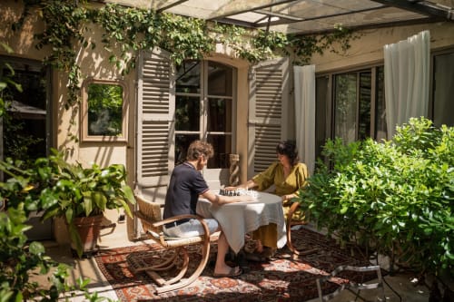 Deux clients jouant aux échecs sur une terrasse ensoleillée aux Jardins de Baracane, un bed and breakfast à Avignon entouré de verdure