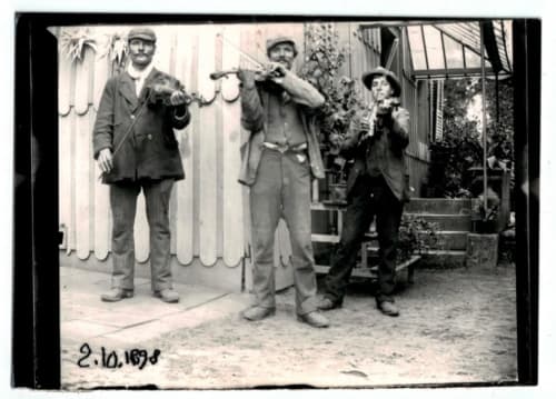 Quatre hommes en costumes vintage jouant des instruments devant la maison oubliée à Goetzenbruck, France