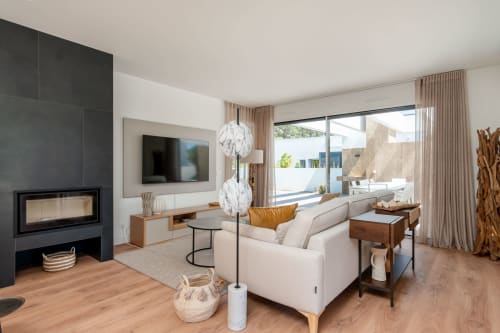 Sala de estar moderna com lareira, sofá bege, piso de madeira e vista para terraço em República do Sul, Aroeira Portugal