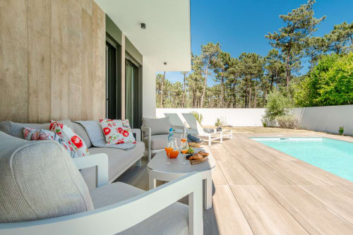Pátio de villa de luxo com móveis contemporâneos, mesa redonda e piscina com vista para a floresta de pinheiros em República do Sul
