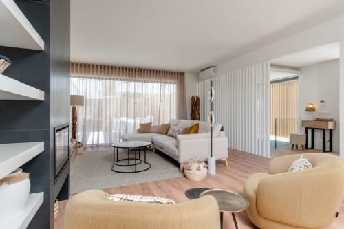 Sala de estar sofisticada em villa moderna com sofá creme, lareira, cortinas verticais e vista para a piscina em República do Sul, Aroeira