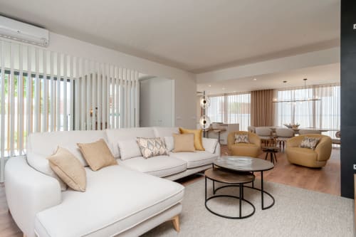 Sala de estar moderna de villa com sofá branco curvilíneo, acessórios dourados e vista para piscina em República do Sul, Aroeira