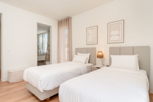 Duas camas de solteiro na suíte Villa Prestige da Quinta do Pinhão, Charneca da Caparica, com cabeceiras bege e decoração moderna