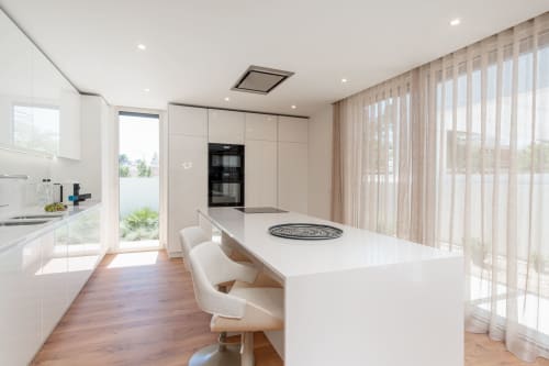 Cozinha moderna de villa com armários brancos, bancada central e vista para o jardim através de janelas do piso ao teto em Republica do