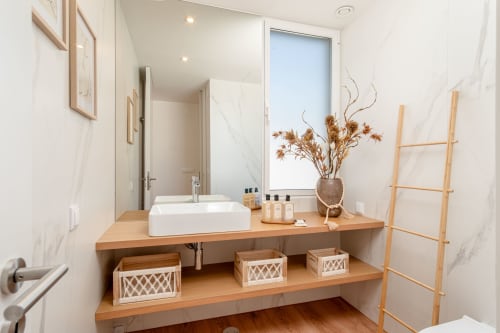 Modern bathroom vanity with white sink, wooden counter, dried flowers, and woven storage baskets in Villa Prestige Quinta do