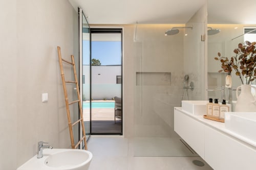 Modern luxury bathroom with rainfall shower, double vanity, and pool view at Vila Prestige, Aroeira Portugal