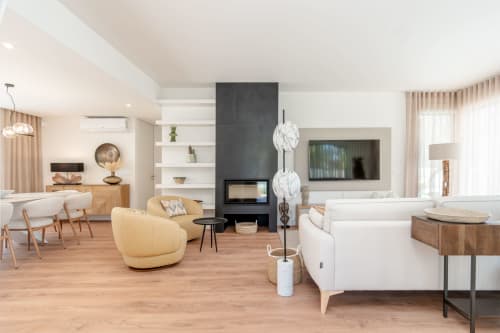 Modern villa living room at Republica do Sul with white sofas, yellow accent chair, fireplace, and wood flooring