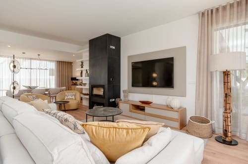 Modern villa living room with white sofa, fireplace, TV, and gold accents at Republica do Sul in Caparica.