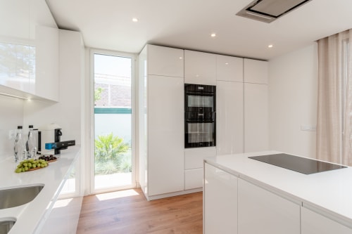 Modern white kitchen with island, stainless steel appliances, and pool view at Villa Prestige Quinta do Pinhao II, Charneca