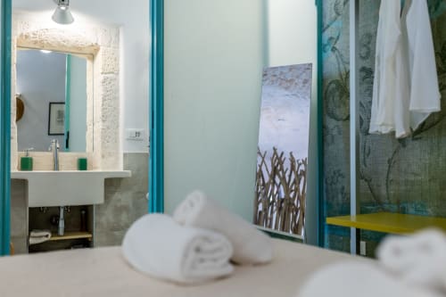 Bagno moderno a Pietra & Luce Ostuni con lavabo, specchio, accenti verdi e opera d'arte con vista mare