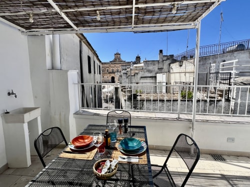 Zona pranzo in terrazza a Pietra & Luce a Ostuni con vista mare e edifici storici imbiancati