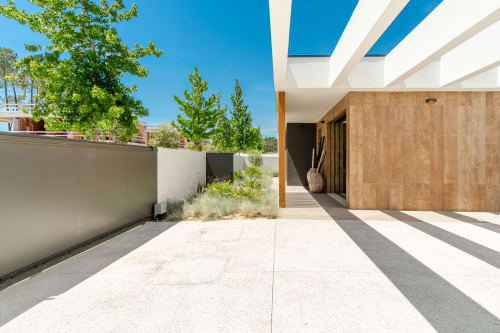 Modern villa courtyard with pergola, light stone paving, wooden cladding, and landscaping at Republica do Sul, Charneca da