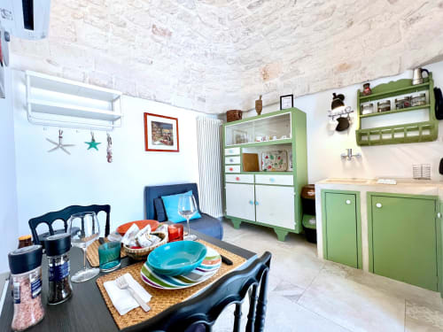 Luminosa area cucina-pranzo con armadi vintage verdi, sedie blu e vista mare presso Pietra & Luce B&B a Ostuni, Italia
