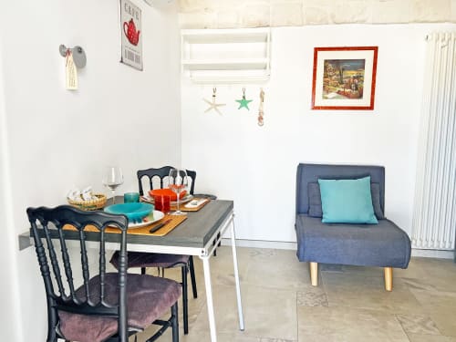 Soggiorno in stile Ostuni con tavolo da pranzo, sedie nere, poltrona blu e vista mare presso Pietra & Luce B&B