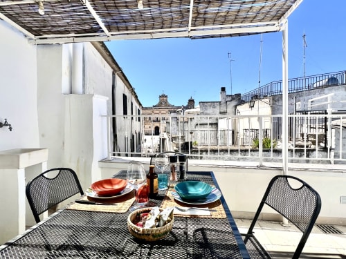 Terrazza sul tetto di Pietra & Luce a Ostuni con tavolo apparecchiato con vista sul mare e sui caratteristici edifici imbiancati