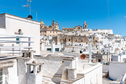 Tetti imbiancati di Ostuni con vista sul mare, dettagli in terracotta e architettura storica in Puglia, Italia