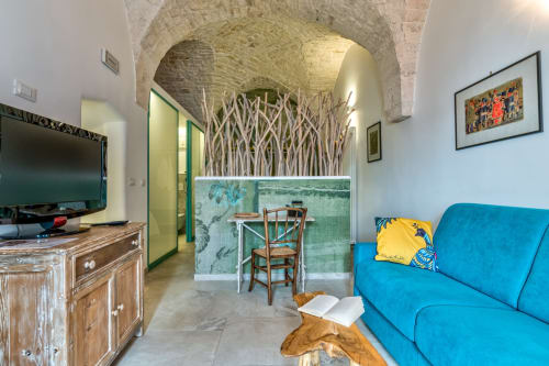 Luminoso soggiorno dell'appartamento di Ostuni con soffitti a volta in pietra, divano blu, TV e arredamento rustico presso Pietra & Luce