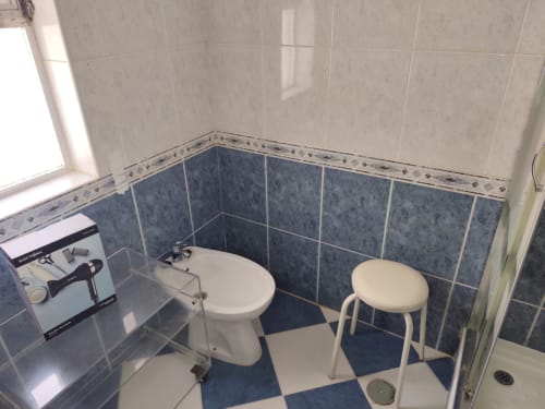 Banheiro com piso de azulejos azuis e brancos, vaso sanitário, banqueta e pia no apartamento Albufeira Inn