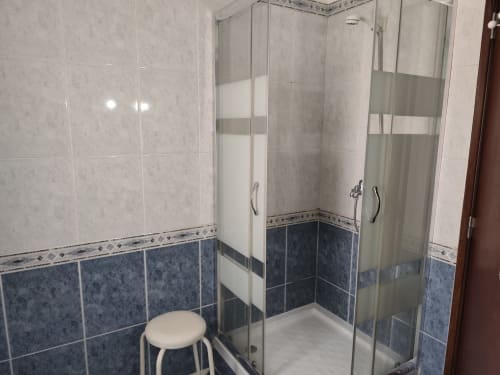 Moderno nicho de duche em vidro com painéis foscos na casa de banho do apartamento Albufeira Inn, design em azulejos azuis e brancos