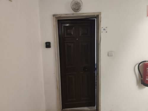 Porta de seis painéis preta com moldura branca no corredor do apartamento em Albufeira, marcado AL