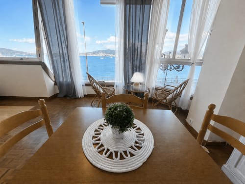 Comedor luminoso del hotel Holibai en Baiona con mesa de madera, vistas al mar a través de amplios ventanales y vista costera