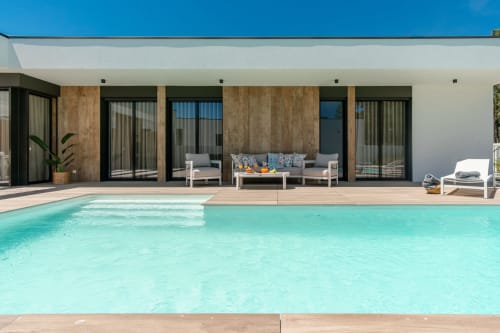 Villa moderna com piscina turquesa, deck de madeira e área de estar em Aroeira, Charneca da Caparica
