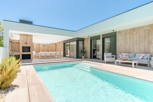 Terraço moderno à beira da piscina com água turquesa, deck de madeira e área de lounging na Republica do Sul em Aroeira
