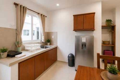 Cocina moderna del Hotel Isla Mujeres Centro con armarios de madera, refrigerador de acero inoxidable y área comedor