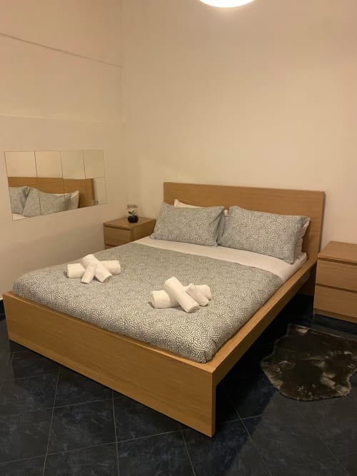 Camera moderna della B&B Fossatello a Genova con letto in legno, biancheria a motivi e vista sulla città