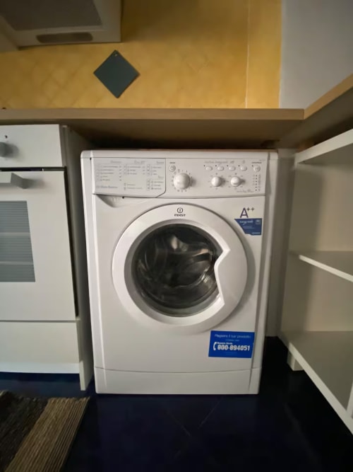 Lavatrice Indesit nell'area lavanderia dell'appartamento a Genova con mobile contenitore integrato