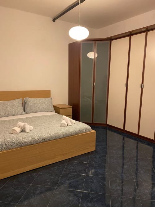 Camera moderna presso B&B Fossatello a Genova con letto in legno, pavimento in piastrelle scure e armadi guardaroba