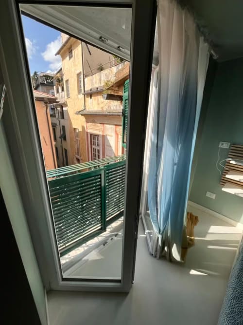 Balcone dell'appartamento a Genova con vista sulla città, persiane verdi affacciate su edifici storici