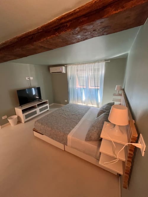 Camera moderna con trave in legno a vista, TV, letto e finestre luminose nella B&B Genova vicino all'Acquario