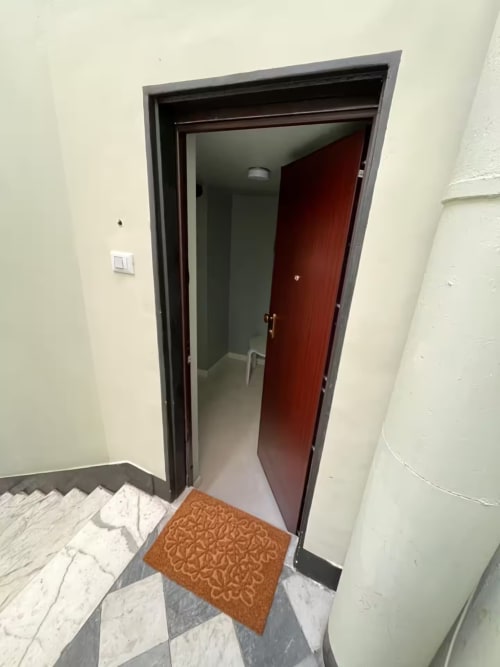 Ingresso del Genova B&B con porta rossa, pavimento in marmo, zerbino marrone e scala