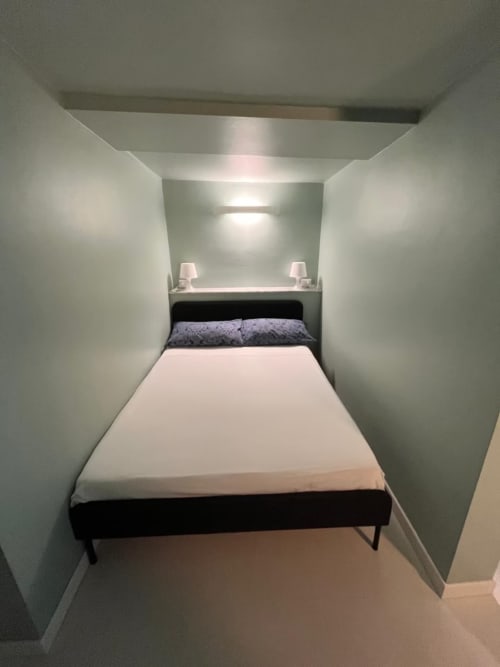 Camera da letto compatta al B&B Fossatello di Genova con letto matrimoniale, pareti bianche, lampade gemelle e design minimale moderno