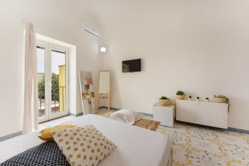 Camera moderna e luminosa di IL POETA Procida B&B con letti gemelli, accenti in legno, piante in vaso e accesso alla terrazza