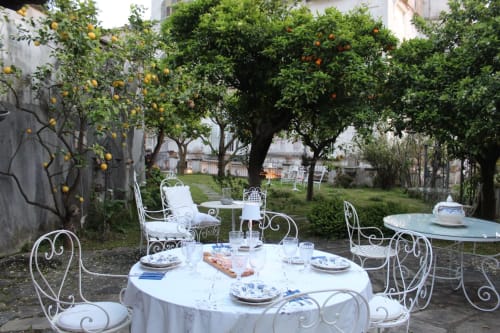 Elegante zona pranzo esterna presso Relais Palazzo Cacace a Meta di Sorrento con mobili in ferro battuto bianco, limoni e aranci