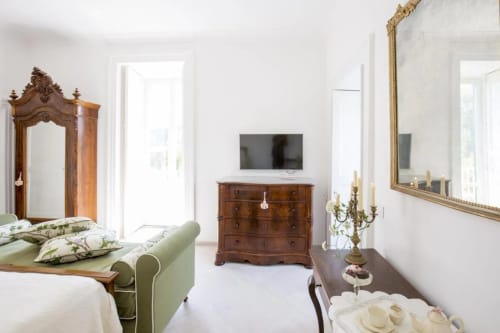 Camera elegante al Relais Palazzo Cacace con letto in velluto verde, mobili in legno antico e vista sul giardino a Meta di