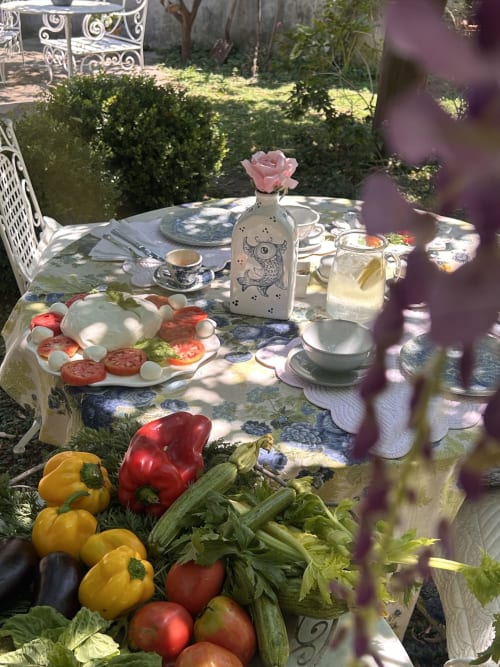 Tavolo in giardino al Relais Palazzo Cacace con prodotti freschi, rosa rosa, coperto elegante e bevande a Meta di