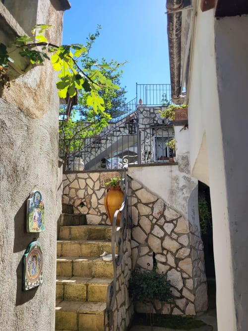 Affascinante scalinata in pietra al Relais Palazzo Cacace a Meta di Sorrento con piastrelle decorative e rigogliosa vegetazione