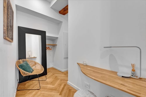 Chambre moderne aux Relais Du Capitole Toulouse avec fauteuil en rotin, bureau en bois et décoration minimaliste