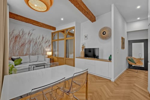 Séjour moderne d'un appartement toulousain avec salle à manger, cuisine, poutres en bois, télévision et salon avec vue sur la ville