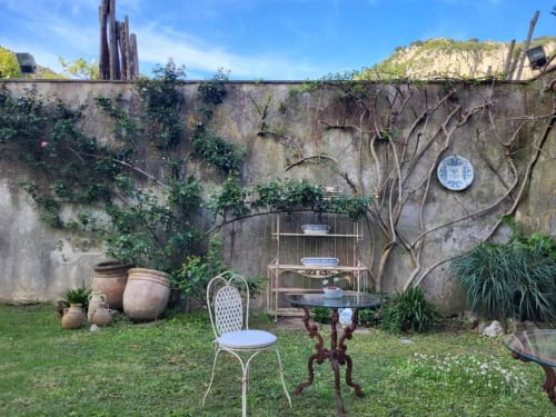 Affascinante cortile interno a Relais Palazzo Cacace a Meta di Sorrento con glicine, ceramiche e arredi vintage