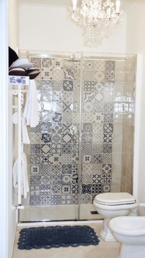 Elegante bagno con doccia in maiolica decorata, sanitari bianchi e lampadario presso Relais Palazzo Cacace a Meta di Sorrento